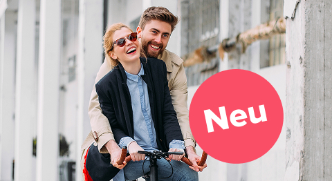 Frau mit bunter Bluse hält ihr Smartphone ins Bild