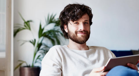 Mann mit Tablet in der Hand lächelt