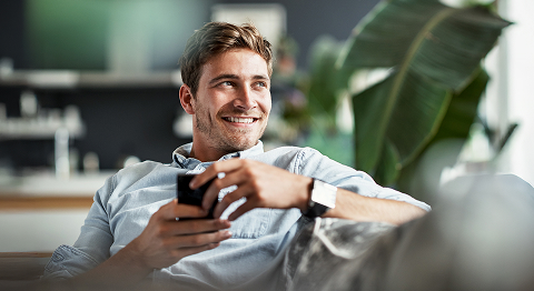 Mann in hellblauem Hemd hält Handy und lächelt