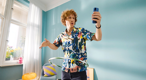 Mann mit buntem Hemd schaut auf sein Smartphone