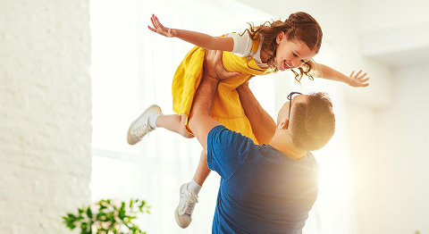 Vater hebt Tochter in die Luft und beide lachen