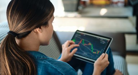 Frau mit langen dunklen Haaren sitzt auf dem Sofa vorm Laptop