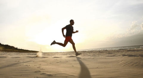 Jogger am Strand bei Sonnenaufgang