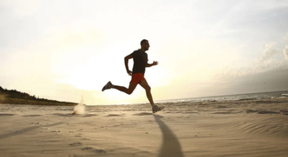 Jogger am Strand bei Sonnenaufgang