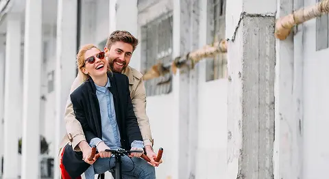 Mann und Frau sitzen zusammen auf einem Fahrrad und lachen