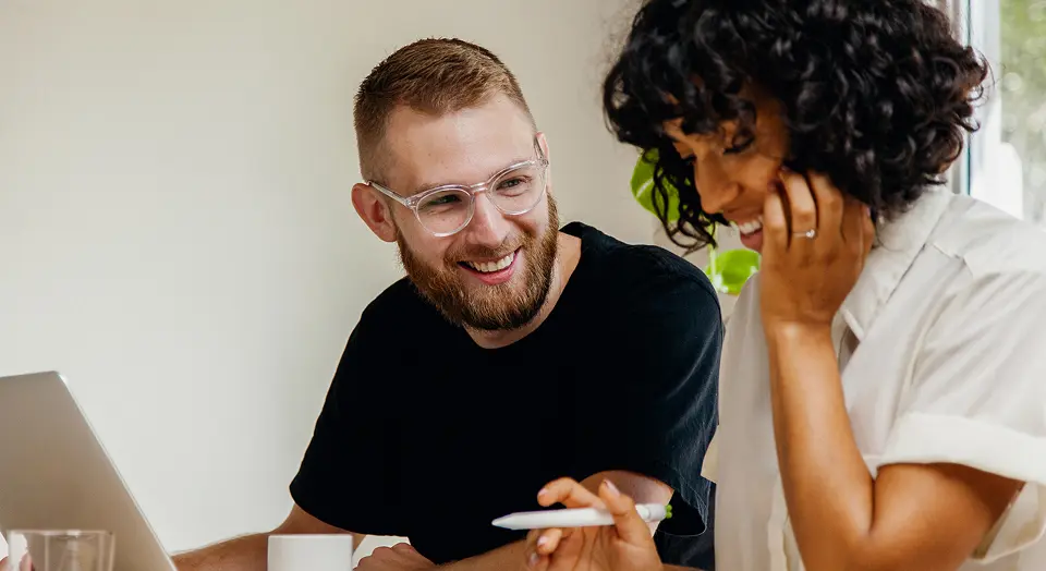 Mann und Frau sitzen gemeinsam am Schreibtisch und machen ihre Steuererklärung am Laptop