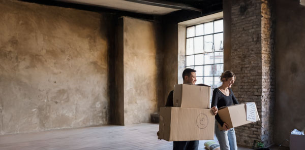 Mann und Frau tragen Umzugskartons aus einem Loft
