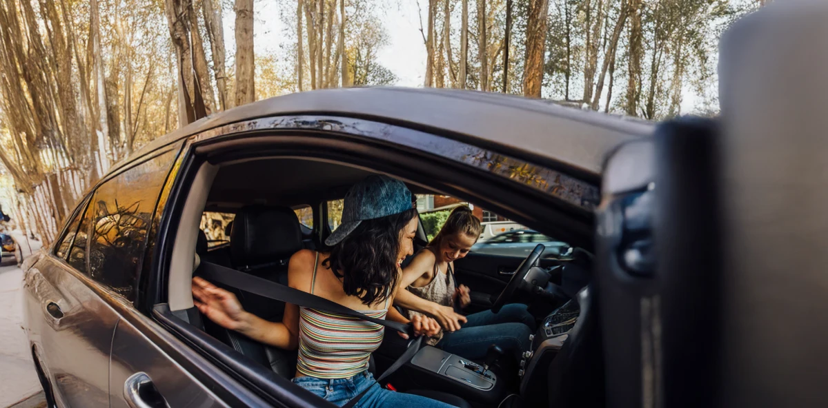 Frau Frauen sitzen im Sommer im Auto und schnallen sich gerade an