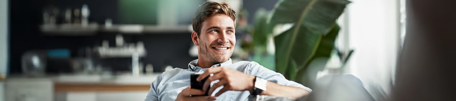Lachender Mann sitzt auf einem Sofa