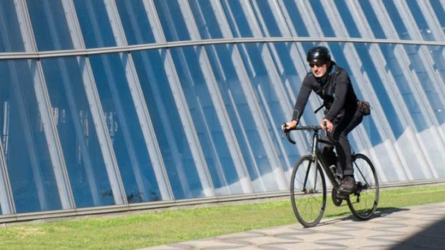 Mann auf dem Fahrrad vor einem Glasgebäude