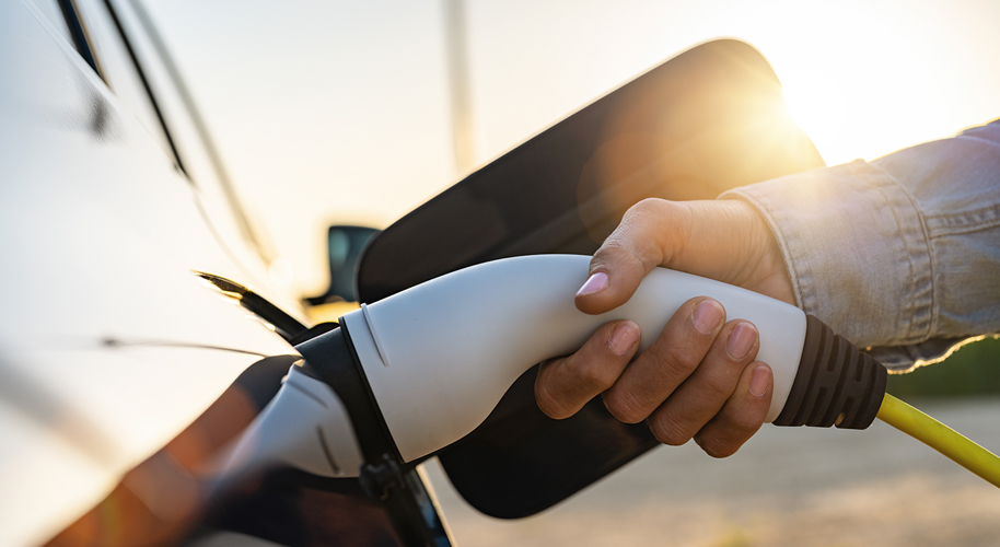 Nahaufnahme einer Hand, die ein E-Auto tankt